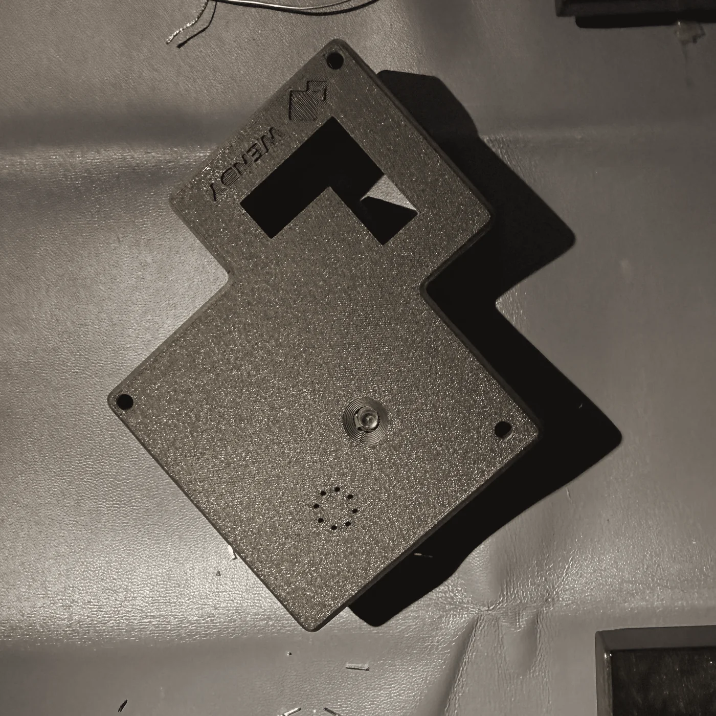 The Wendy Tag prototype case, shaped like the Wendy emblem, with camera lens and microphone holes